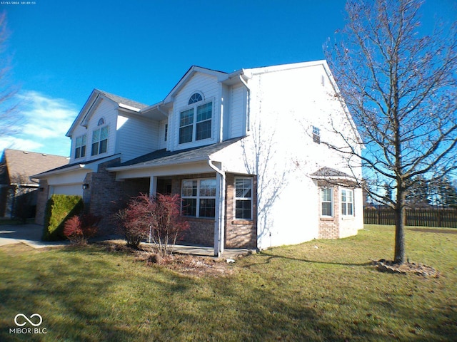 view of home's exterior featuring driveway, a lawn, an attached garage, fence, and brick siding