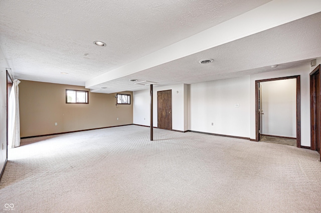 below grade area featuring visible vents, light colored carpet, and baseboards