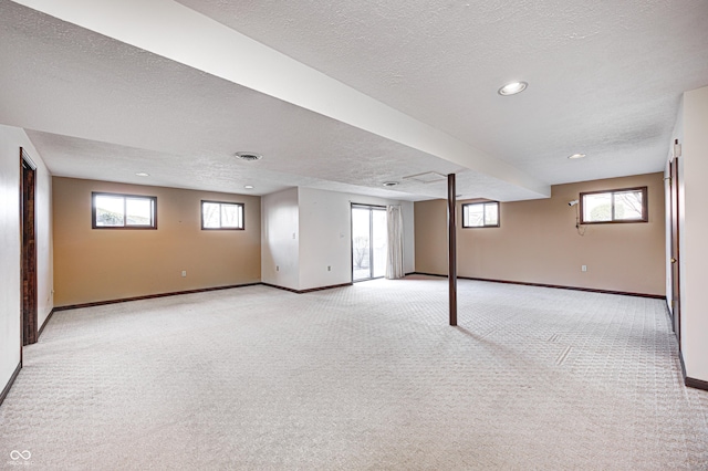 basement featuring visible vents, baseboards, recessed lighting, a textured ceiling, and light carpet