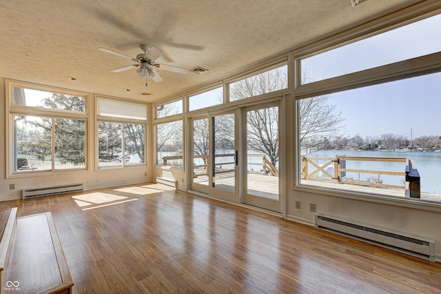 unfurnished sunroom with visible vents, a baseboard heating unit, ceiling fan, and a water view