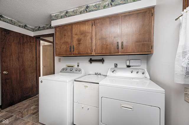 laundry room featuring a textured ceiling, cabinet space, and washing machine and clothes dryer