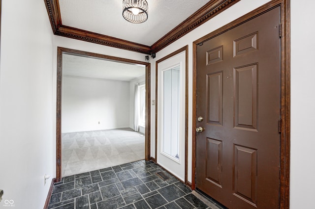 entrance foyer with a textured ceiling, stone finish flooring, baseboards, and ornamental molding