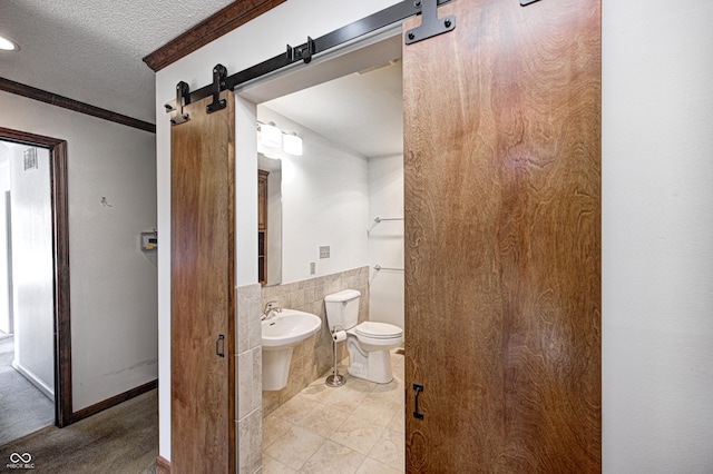 half bath featuring tile walls, toilet, wainscoting, tile patterned floors, and a textured ceiling