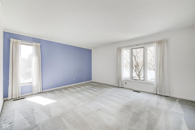 empty room with visible vents, plenty of natural light, carpet, and crown molding