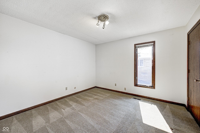 unfurnished room with light carpet, visible vents, a textured ceiling, and baseboards