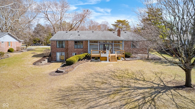 back of house with a lawn, a deck, a sunroom, brick siding, and a chimney