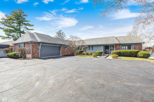 view of front of house with an attached garage, brick siding, driveway, and a shingled roof