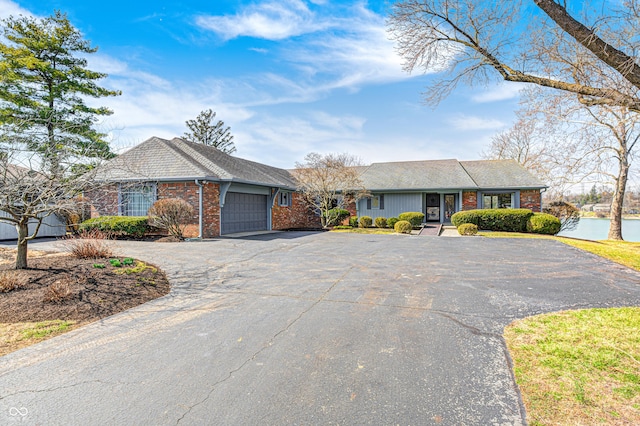 ranch-style home featuring brick siding, driveway, and a garage