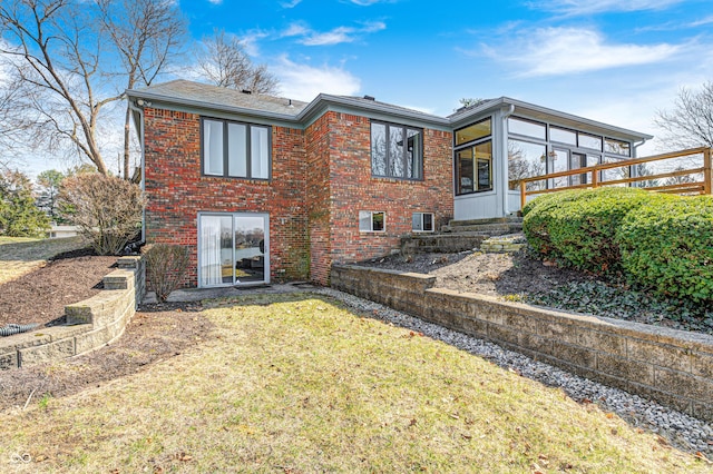 rear view of property featuring a yard, brick siding, and a sunroom