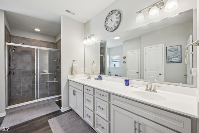 bathroom featuring visible vents, a shower stall, wood finished floors, and a sink