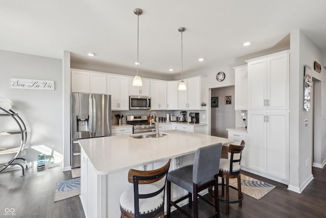 kitchen with decorative backsplash, white cabinets, appliances with stainless steel finishes, and a sink