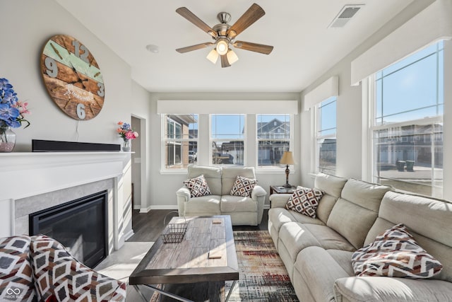 living area featuring visible vents, ceiling fan, baseboards, a fireplace with flush hearth, and wood finished floors