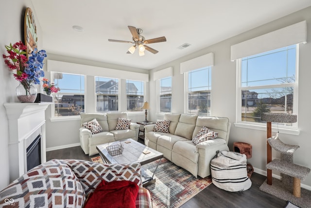 living area with visible vents, a ceiling fan, wood finished floors, a fireplace, and baseboards