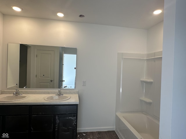 bathroom with double vanity, wood finished floors, a sink, and recessed lighting