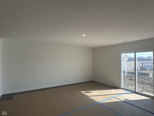 spare room featuring baseboards, visible vents, and a textured ceiling