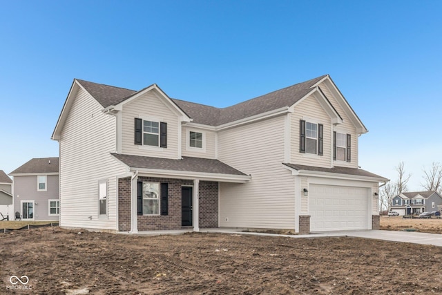 traditional-style home with an attached garage, a shingled roof, concrete driveway, and brick siding