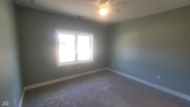 unfurnished room with a ceiling fan, baseboards, and dark colored carpet