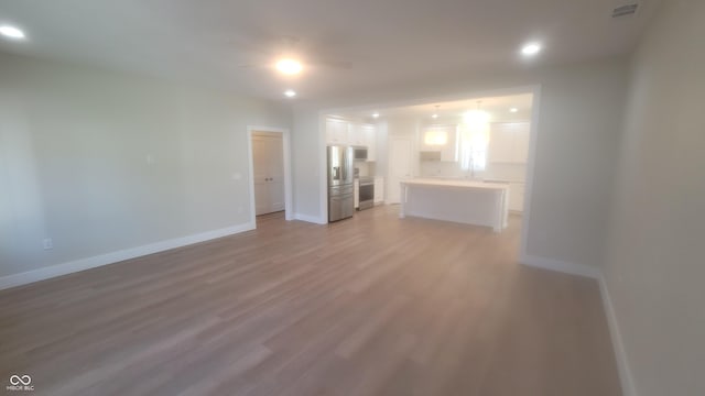 unfurnished living room with light wood finished floors, visible vents, recessed lighting, and baseboards