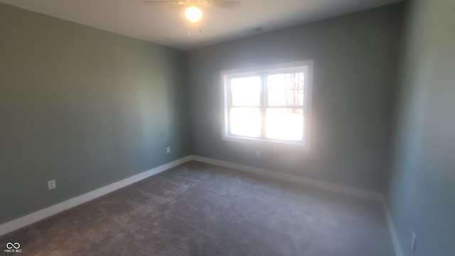 unfurnished room with baseboards, ceiling fan, and dark carpet