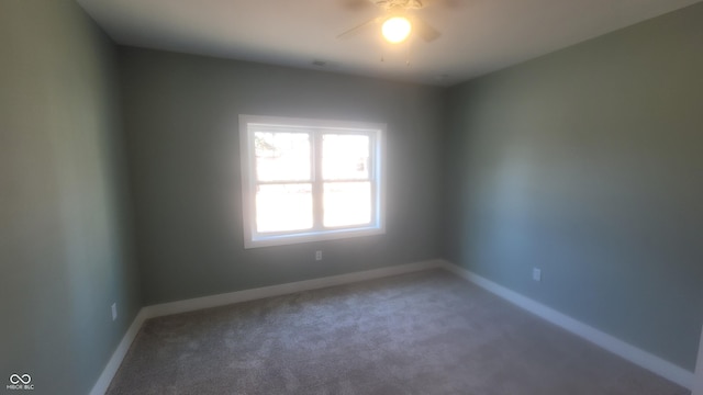 carpeted spare room featuring a ceiling fan and baseboards