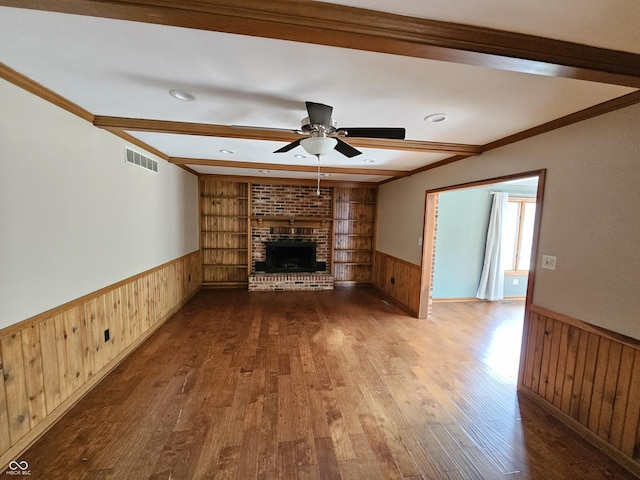 unfurnished living room featuring built in features, wainscoting, visible vents, and beam ceiling