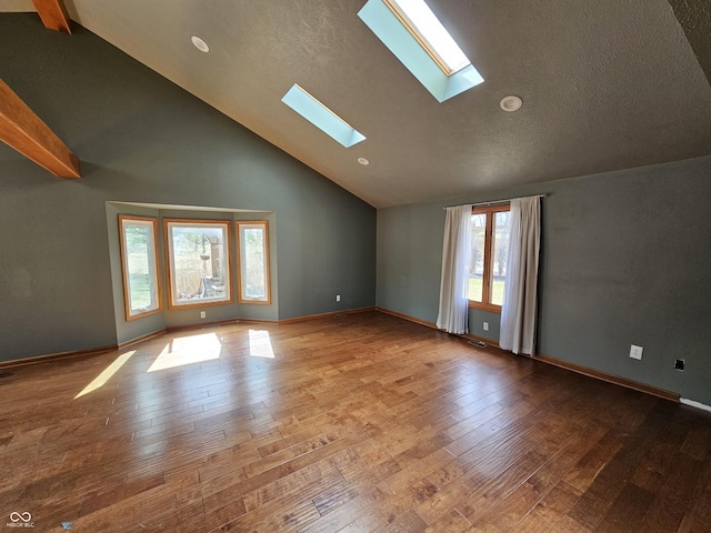 spare room featuring a textured ceiling, high vaulted ceiling, wood-type flooring, and a skylight