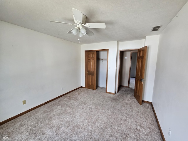 unfurnished bedroom with carpet, visible vents, a textured ceiling, and baseboards