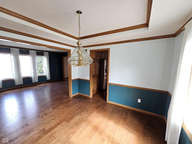 unfurnished dining area with a tray ceiling, baseboards, ornamental molding, and wood finished floors