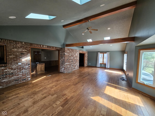 unfurnished living room with a skylight, plenty of natural light, beam ceiling, and hardwood / wood-style flooring