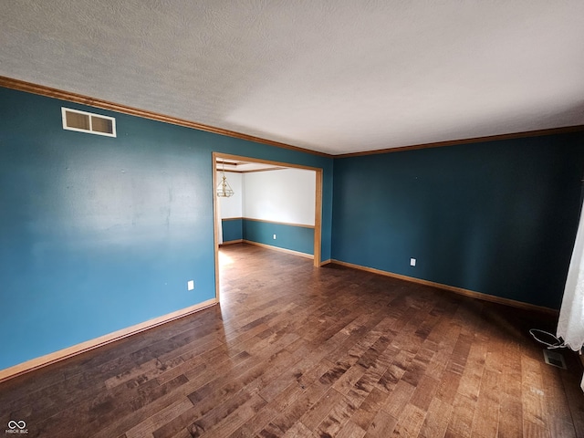 unfurnished room with a textured ceiling, wood finished floors, visible vents, and crown molding