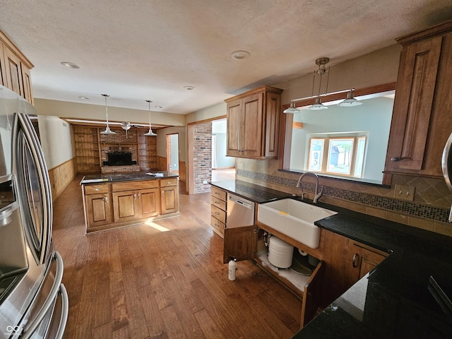 kitchen featuring stainless steel appliances, a sink, light wood-style flooring, and pendant lighting