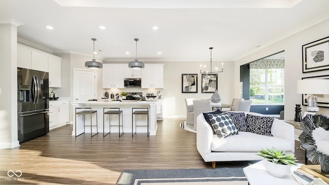 living room featuring an inviting chandelier, baseboards, ornamental molding, and wood finished floors