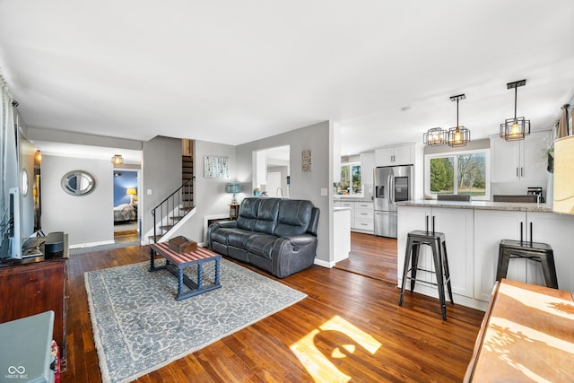 living area with stairs, dark wood-type flooring, and baseboards