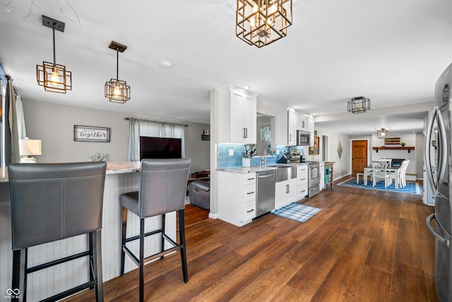 kitchen featuring white cabinets, backsplash, dark wood-style flooring, and appliances with stainless steel finishes