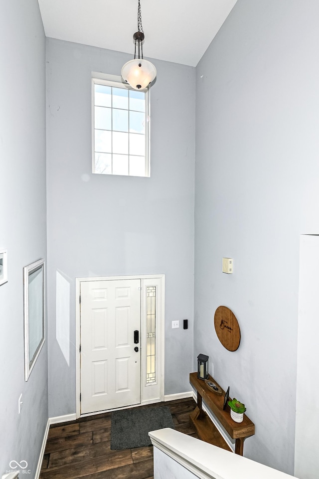 entrance foyer featuring a towering ceiling, baseboards, and dark wood-type flooring