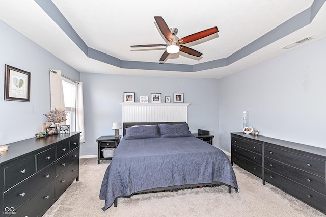 carpeted bedroom featuring a ceiling fan, a raised ceiling, visible vents, and baseboards