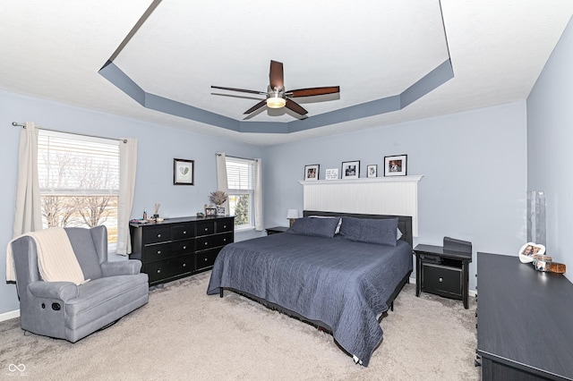 bedroom with ceiling fan, carpet floors, and a raised ceiling