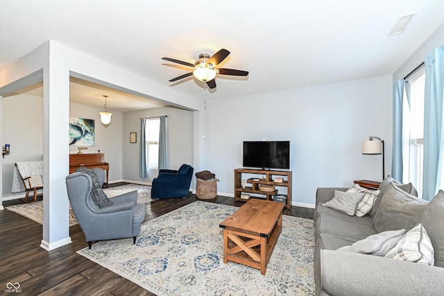 living room with ceiling fan, dark wood-type flooring, visible vents, and baseboards