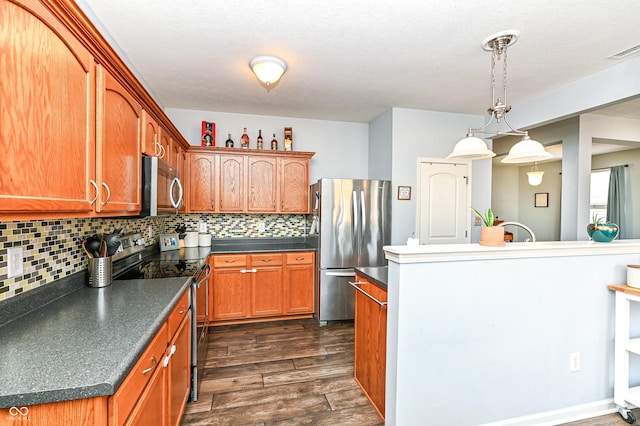 kitchen featuring dark wood-style flooring, stainless steel appliances, dark countertops, visible vents, and decorative backsplash