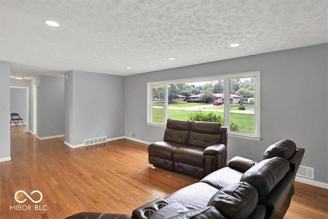 living area with visible vents, baseboards, and wood finished floors