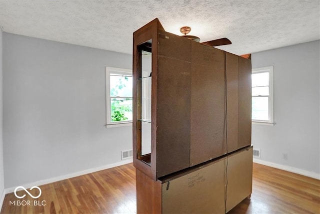 kitchen with a healthy amount of sunlight, a textured ceiling, baseboards, and wood finished floors