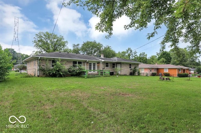 rear view of property featuring a yard, fence, and a chimney