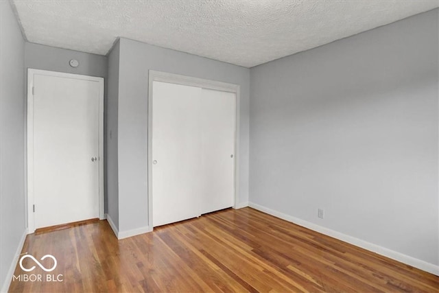 unfurnished bedroom with wood finished floors, a closet, and baseboards