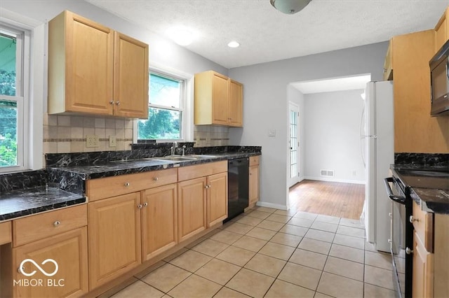 kitchen featuring a sink, tasteful backsplash, black appliances, and light tile patterned floors