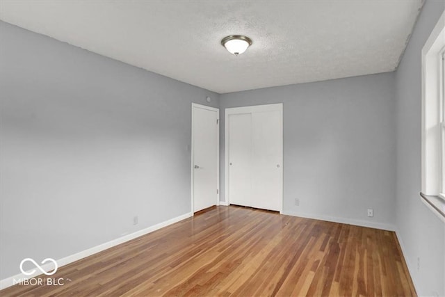 unfurnished room featuring wood finished floors, baseboards, and a textured ceiling