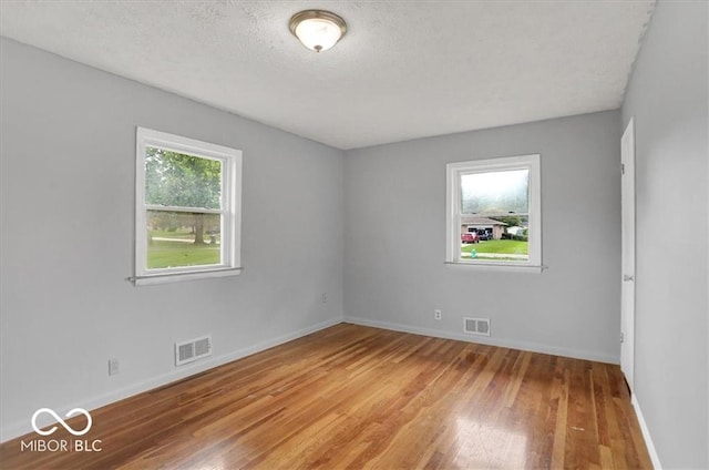 empty room with visible vents, a healthy amount of sunlight, and light wood-type flooring