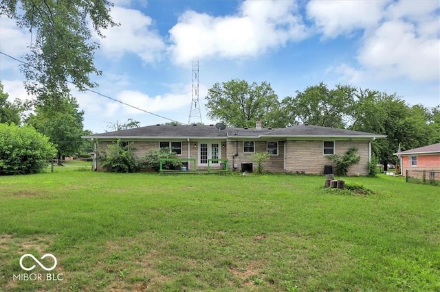 back of house featuring stone siding, a lawn, french doors, and a chimney