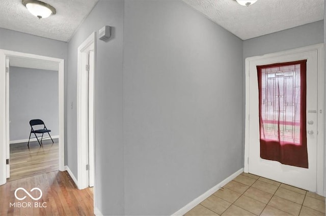 foyer entrance featuring light tile patterned floors, baseboards, and a textured ceiling