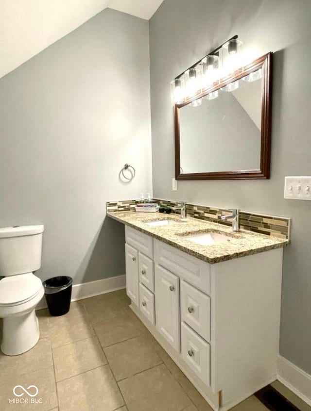 bathroom with lofted ceiling, a sink, toilet, and baseboards