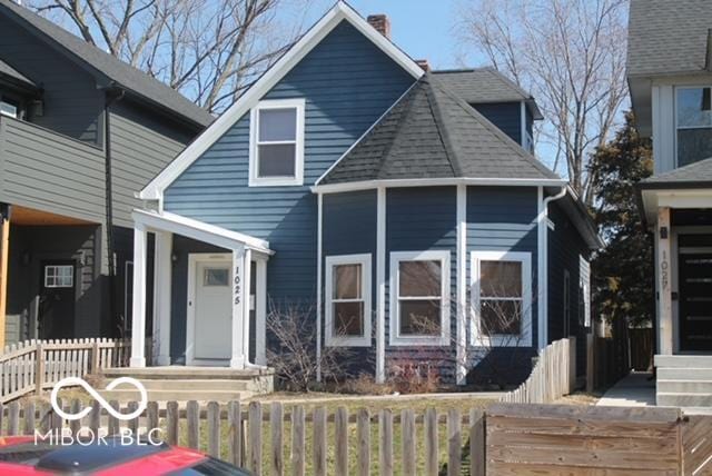 exterior space with a shingled roof and a fenced front yard